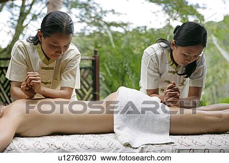Two masseuses massaging a woman’s body. View Large Photo Image Stock Image - Two masseuses massaging a woman’s body.. Fotosearch