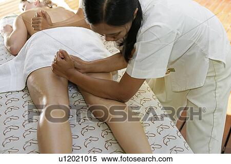 Two masseuses massaging a young woman’s body. View Large Photo Image Stock Photography - Two masseuses massaging a young woman’s body.. Fotosearch
