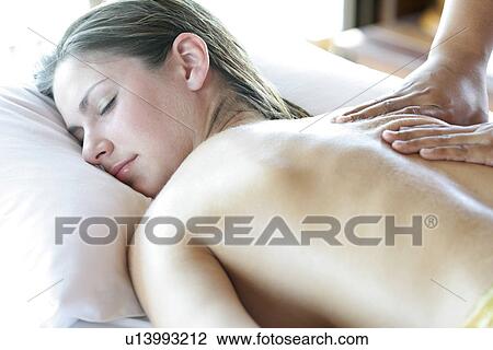 Stock Image - A person massaging a young woman’s back.. Fotosearch