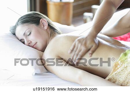 Stock Photograph - A person massaging a young woman’s back.. Fotosearch