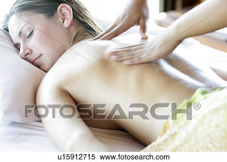 Stock Photography - A person massaging a young woman’s back.. Fotosearch