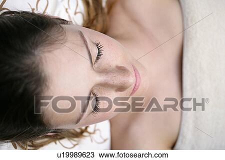 Stock Image - A young woman lying with eyes closed.. Fotosearch