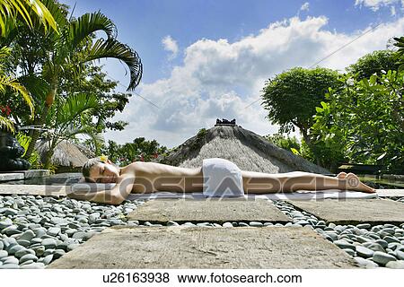 Stock Photo - A young woman sun bathing beside a pool.. Fotosearch