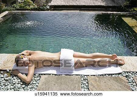 A young woman sun bathing beside a pool. View Large Photo Image Stock Photography - A young woman sun bathing beside a pool.. Fotosearch