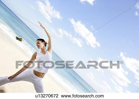 A woman exercising on a beach with hand raised. View Large Photo Image Stock Image - A woman exercising on a beach with hand raised.. Fotosearch