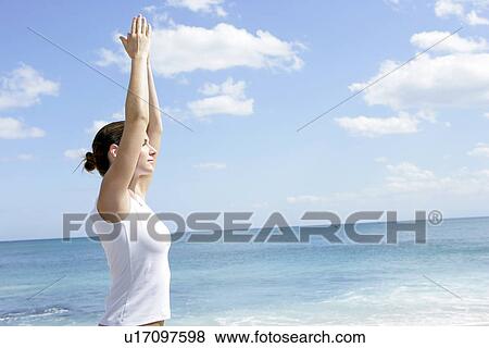 A woman exercising on a beach with hands raised. View Large Photo Image Stock Photo - A woman exercising on a beach with hands raised.. Fotosearch