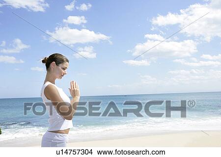 A woman meditating on a beach with joined hands. View Large Photo Image Picture - A woman meditating on a beach with joined hands.. Fotosearch
