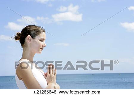 A woman meditating on a beach with joined hands. View Large Photo Image Stock Photograph - A woman meditating on a beach with joined hands.. Fotosearch