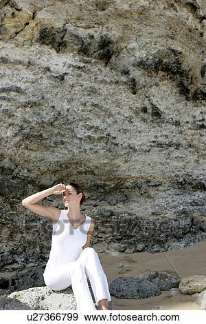 A woman sitting on rocks. View Large Photo Image Stock Photo - A woman sitting on rocks.. Fotosearch