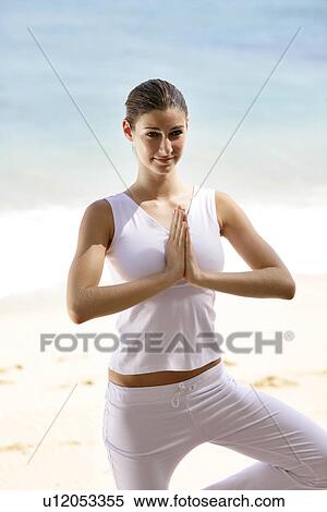 Stock Photography - A woman standing with joined hands on a beach.. Fotosearch