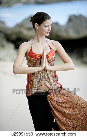 Stock Image - A woman standing with joined hands.. Fotosearch