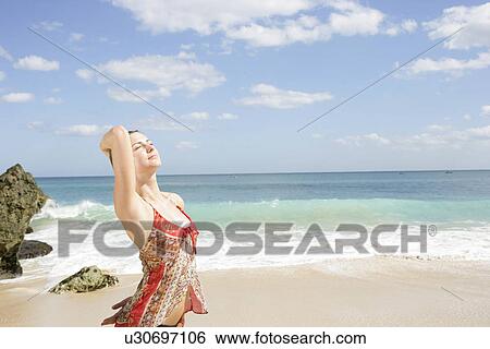 A young woman standing along seashore. View Large Photo Image Stock Photograph - A young woman standing along seashore.. Fotosearch