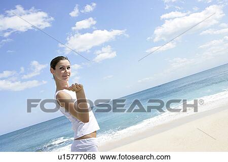A young woman standing on a beach. View Large Photo Image Stock Photo - A young woman standing on a beach.. Fotosearch