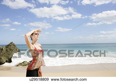 A young woman standing on a beach. View Large Photo Image Stock Photo - A young woman standing on a beach.. Fotosearch