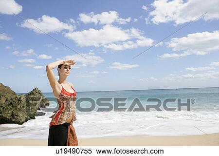Stock Photography - A young woman standing on a beach.. Fotosearch