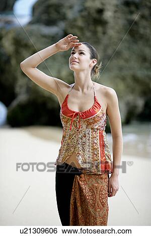 Stock Photograph - View of a woman shielding her eyes.. Fotosearch