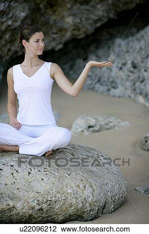 View of a woman sitting with cross legged on a rock. View Large Photo Image Stock Image - View of a woman sitting with cross legged on a rock.. Fotosearch