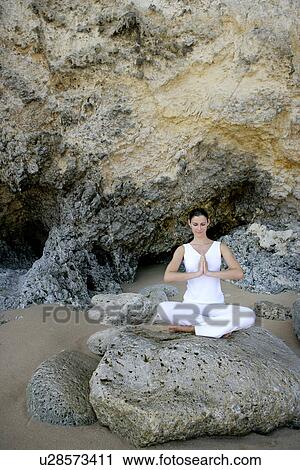 Stock Image - View of a woman sitting with cross legged on a rock.. Fotosearch
