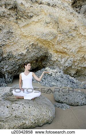 View of a woman sitting with cross legged on a rock. View Large Photo Image Stock Photo - View of a woman sitting with cross legged on a rock.. Fotosearch