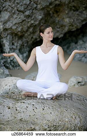 Stock Photo - View of a woman sitting with cross legged on a rock.. Fotosearch