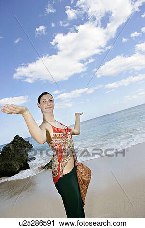 Stock Image - View of a woman with arms out on a beach.. Fotosearch