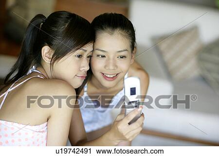 Young women looking at mobile phone. View Large Photo Image Stock Image - Young women looking at mobile phone.. Fotosearch