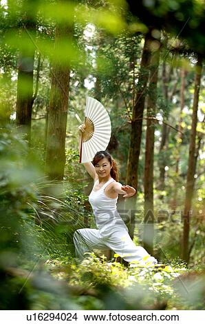 View of a young woman exercising in a forest. View Large Photo Image Picture - View of a young woman exercising in a forest.. Fotosearch