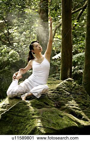 Stock Image - View of a young woman exercising in a forest.. Fotosearch
