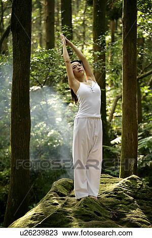 Stock Image - View of a young woman exercising in a forest.. Fotosearch