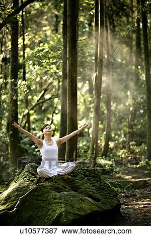 Stock Photo - View of a young woman exercising in a forest.. Fotosearch