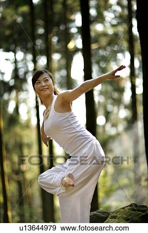 Stock Photo - View of a young woman exercising in a forest.. Fotosearch