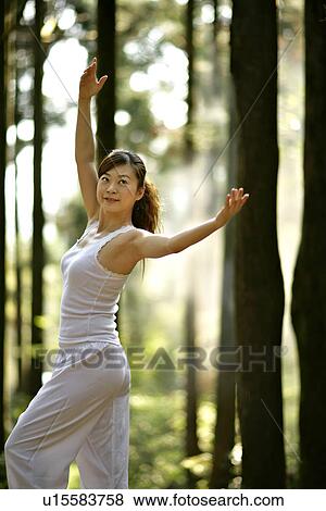 Stock Photo - View of a young woman exercising in a forest.. Fotosearch