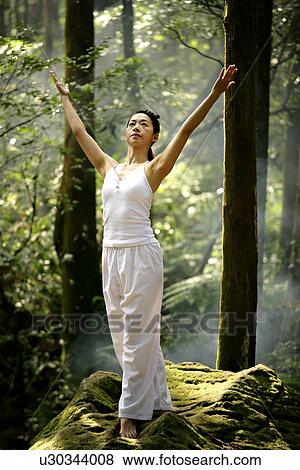 View of a young woman exercising in a forest. View Large Photo Image Stock Photo - View of a young woman exercising in a forest.. Fotosearch
