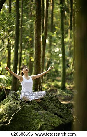 Stock Photography - View of a young woman exercising in a forest.. Fotosearch