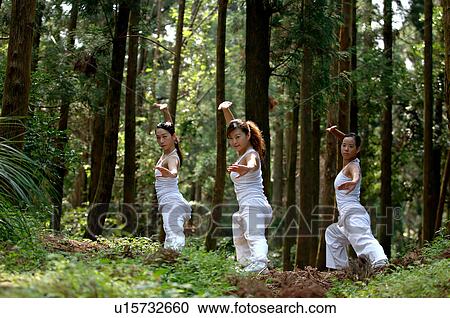 Stock Image - View of young women exercising in a forest.. Fotosearch