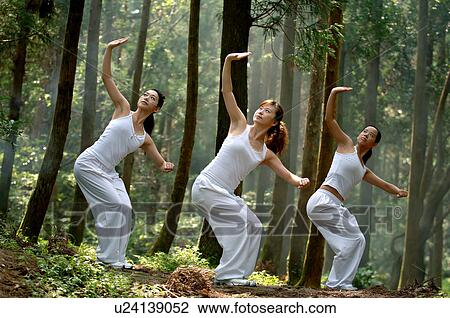 Stock Image - View of young women exercising in a forest.. Fotosearch