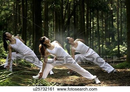 Stock Image - View of young women exercising in a forest.. Fotosearch