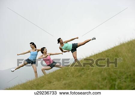 View of young women exercising on grassland. View Large Photo Image Stock Image - View of young women exercising on grassland.. Fotosearch