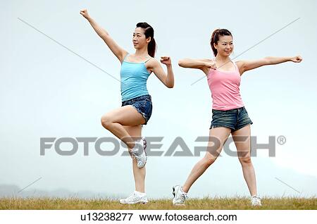 Stock Photo - View of young women exercising on grassland.. Fotosearch