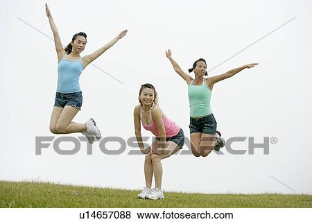 Stock Photo - View of young women exercising on grassland.. Fotosearch