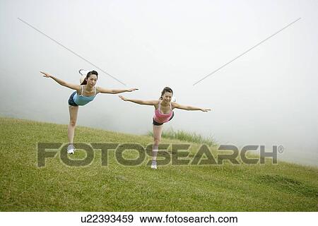 Stock Photo - View of young women exercising on grassland.. Fotosearch
