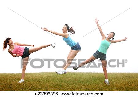 Stock Photograph - View of young women exercising on grassland.. Fotosearch