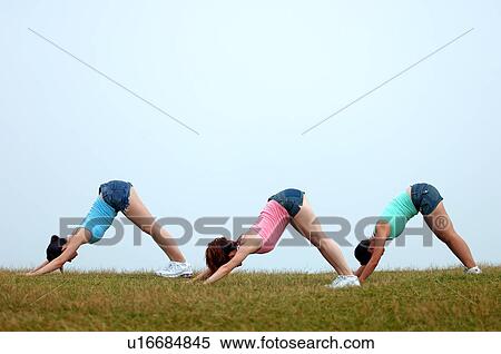 Stock Photography - View of young women exercising on grassland.. Fotosearch