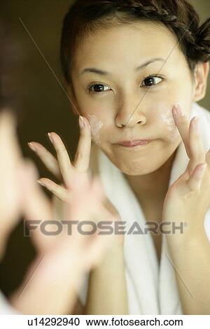 View of a woman applying a lotion on her face. View Large Photo Image Stock Image - View of a woman applying a lotion on her face.. Fotosearch