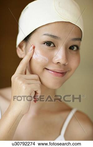 View of a woman applying cream on her cheeks. View Large Photo Image Picture - View of a woman applying cream on her cheeks.. Fotosearch