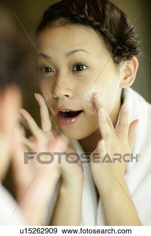 View of a woman applying lotion on her face. View Large Photo Image Stock Photo - View of a woman applying lotion on her face.. Fotosearch