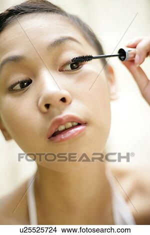 View of a woman applying mascara. View Large Photo Image Picture - View of a woman applying mascara.. Fotosearch