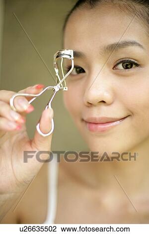 View of a young woman with an eyelash curler. View Large Photo Image Stock Image - View of a young woman with an eyelash curler.. Fotosearch