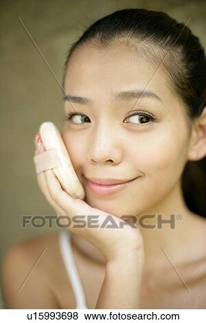 Stock Photo - Close-up of a young woman applying powder puff.. Fotosearch