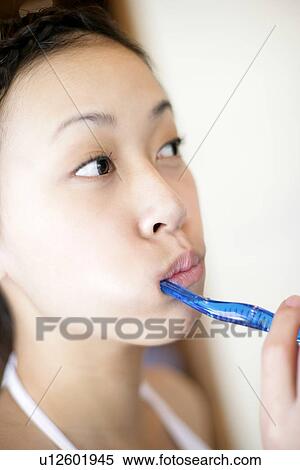 Stock Photography - Close-up of a young woman brushing teeth.. Fotosearch